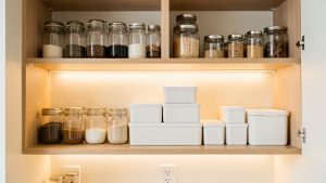 Placards de cuisine lumineux et bien organisés, avec des bocaux transparents et des boîtes hermétiques dans une ambiance chaleureuse.