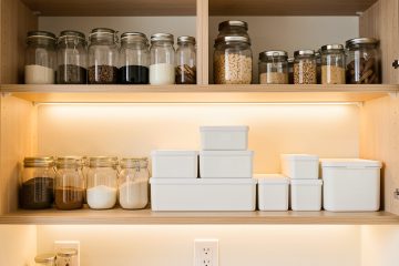 Placards de cuisine lumineux et bien organisés, avec des bocaux transparents et des boîtes hermétiques dans une ambiance chaleureuse.