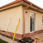 Rénovation extérieure maison : 8 vérifications avant l’artisan Façade extérieure d’une maison observée avec des outils de mesure et de vérification avant des travaux de rénovation.